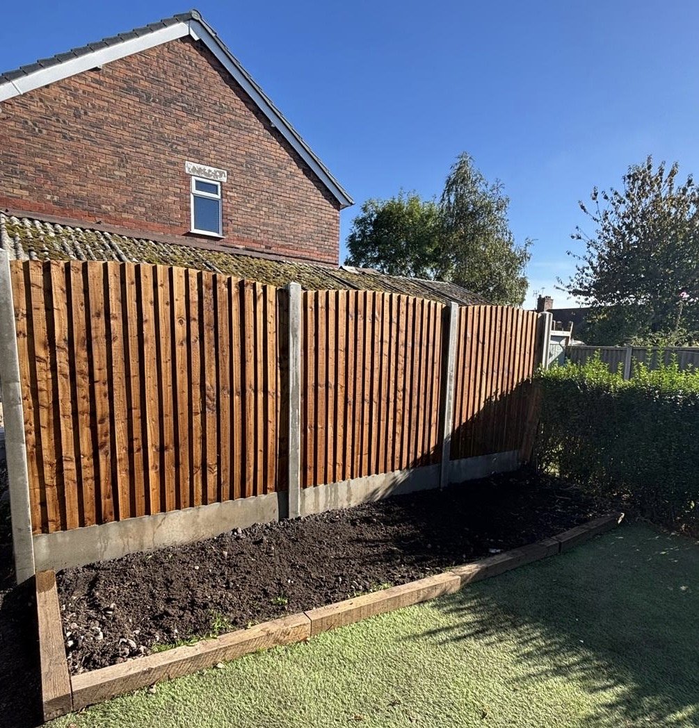 New closeboard timber fence on concrete posts and gravel boards, with a sleeper-edged border in front