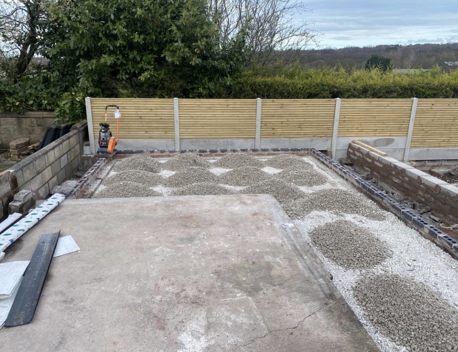 Brick and block perimeter built with stone sub-base being laid, new slatted fence on concrete posts behind